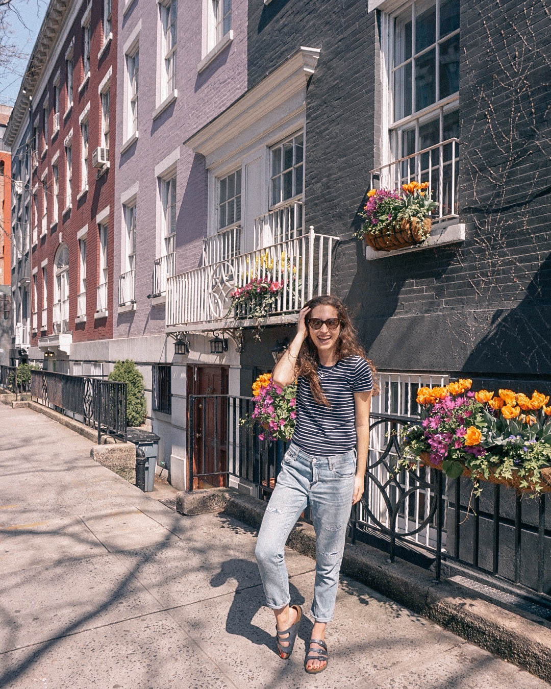 Woman smiling on sidewalk in Greenwich Village NYC on spring day