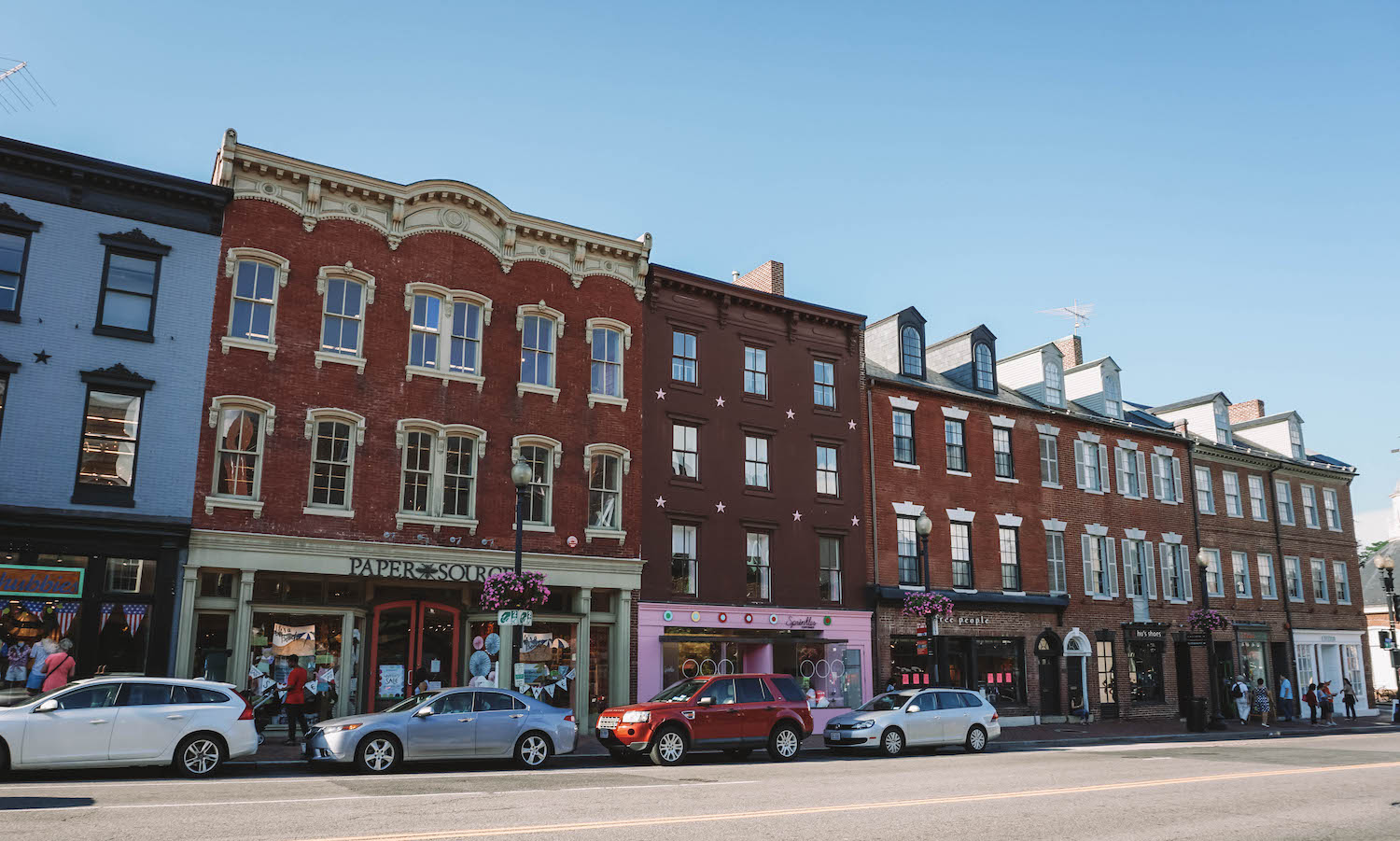 Front view of the main shopping street in Georgetown. Cars are lined up along the sidewalk. 