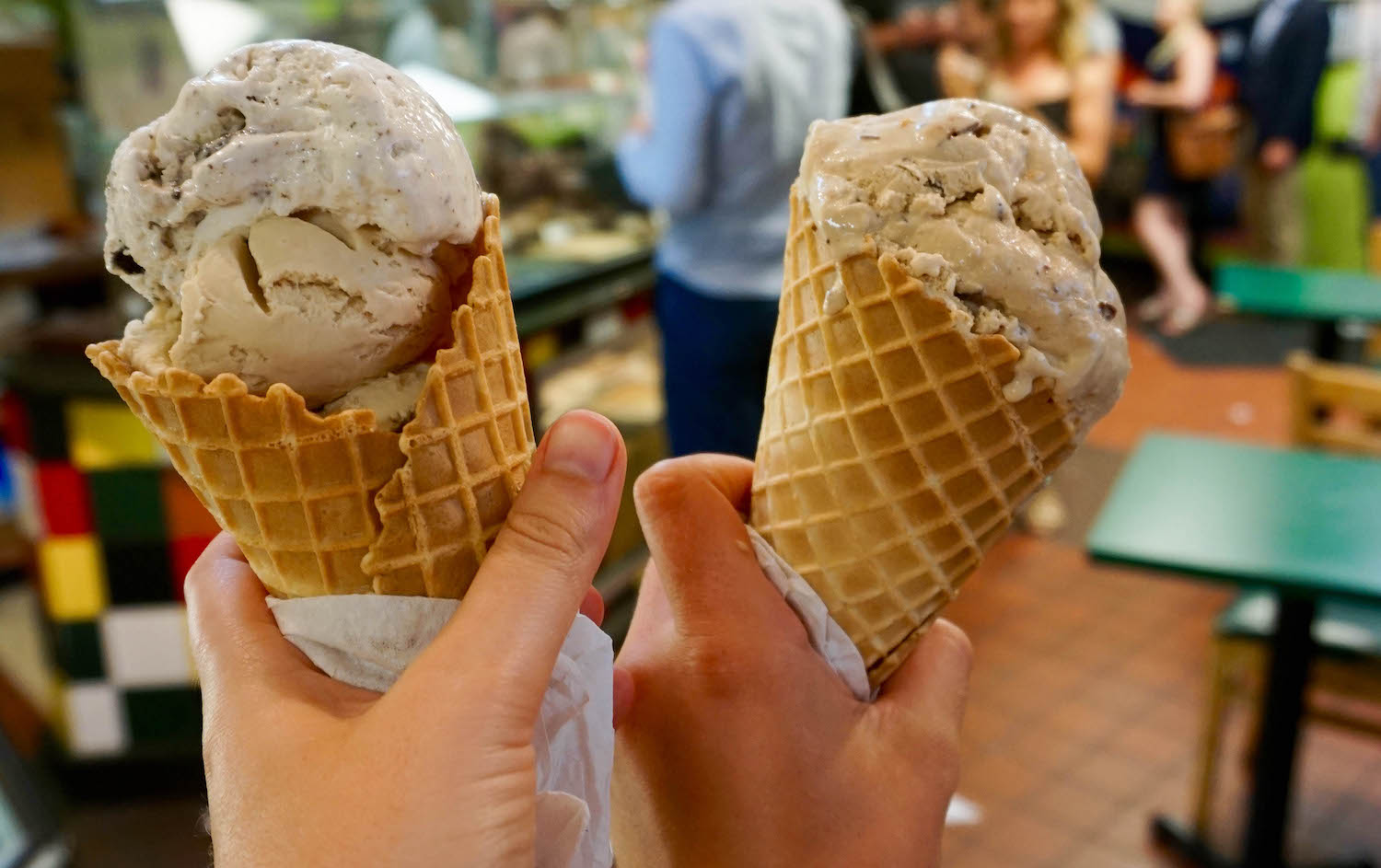 Two large ice cream cones being held aloft in Thomas' Sweet. 