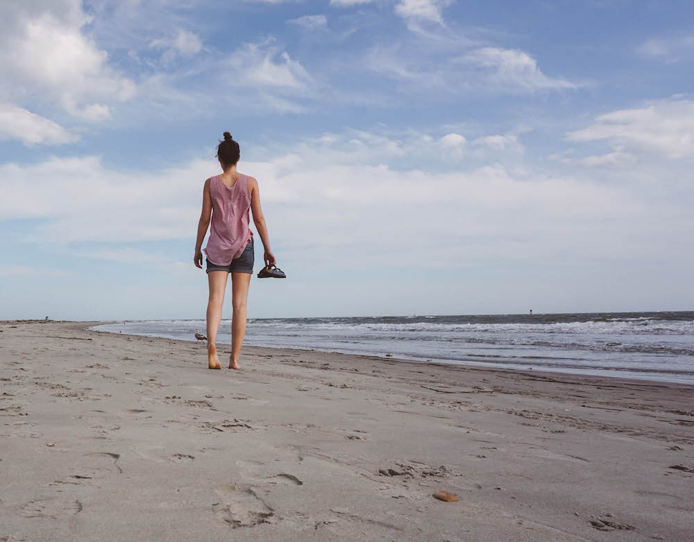 A woman walking along the beach of Sullivan's Island. 