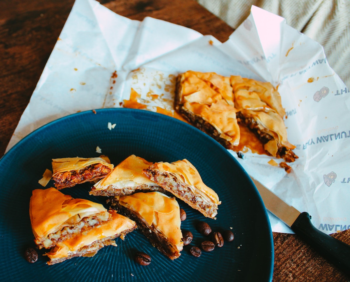 Baklava on a dark plate, with more in a nearby wrapper.