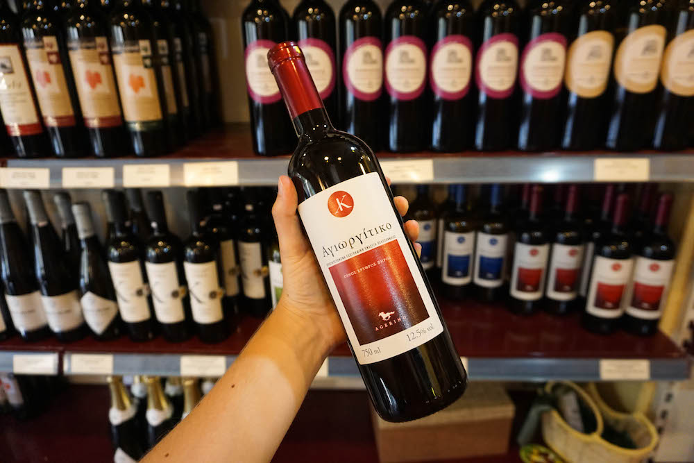 A bottle of Greek red wine being held aloft. 