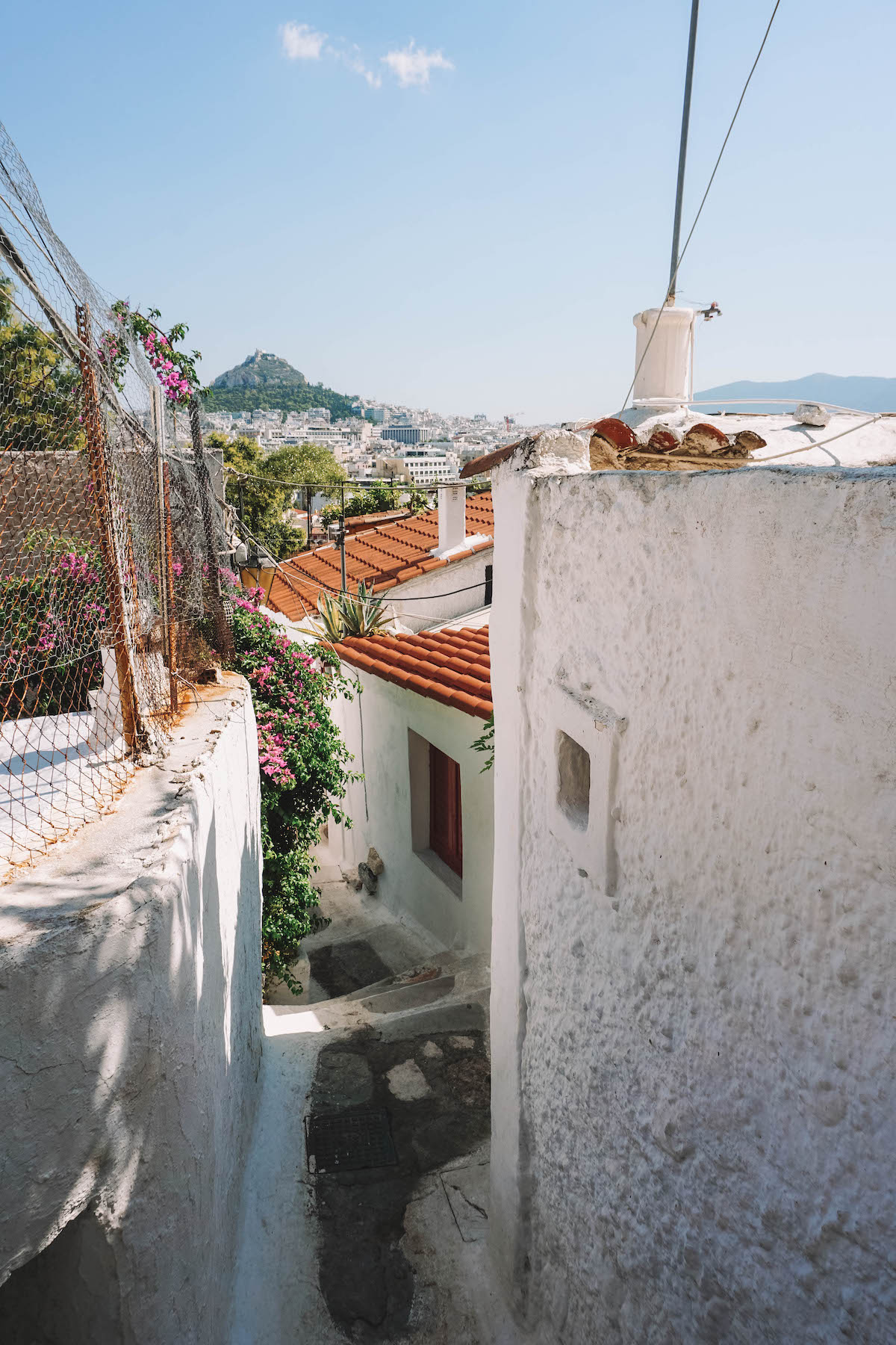 A look down a winding path in Anafiotika, with Mount Lycabettus in the background. 