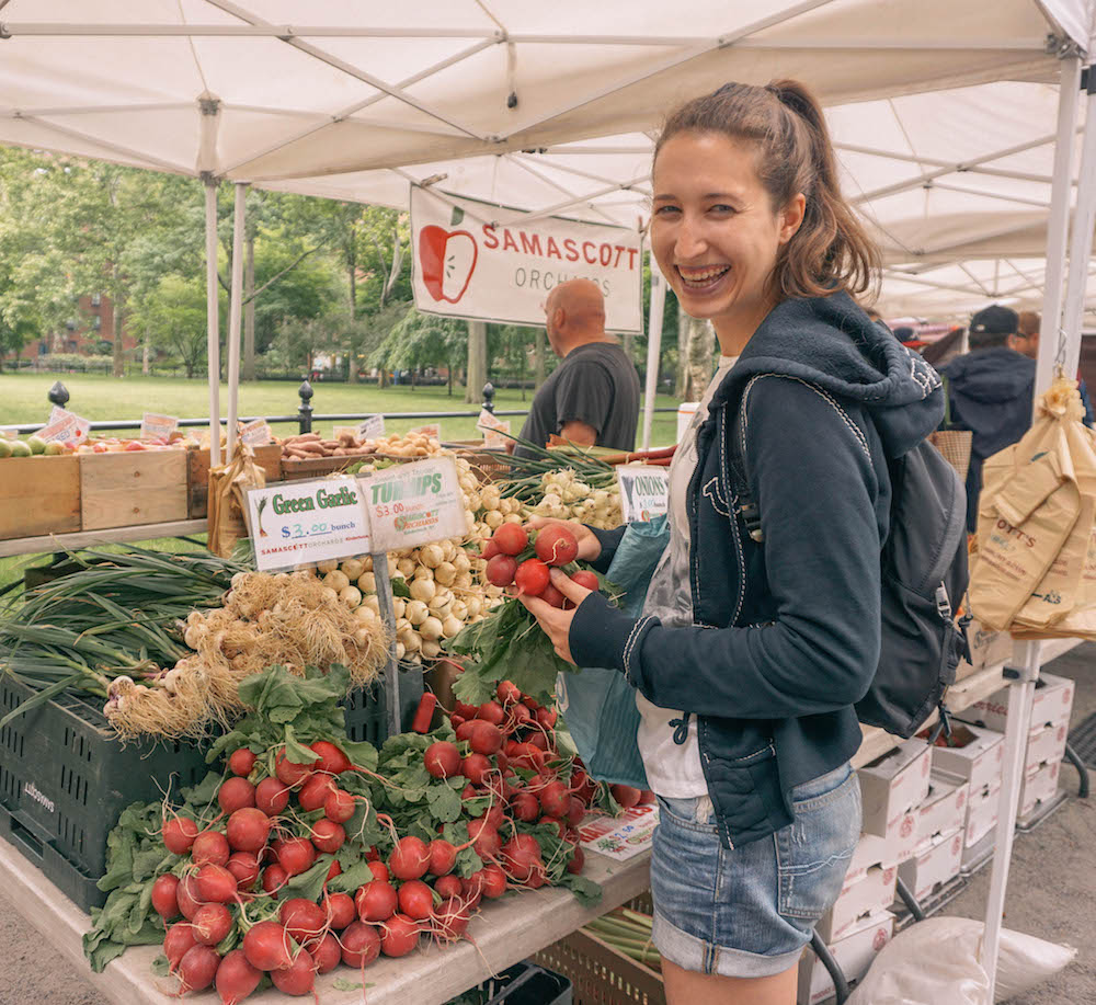 Woman holding radishes at NYC farmers market