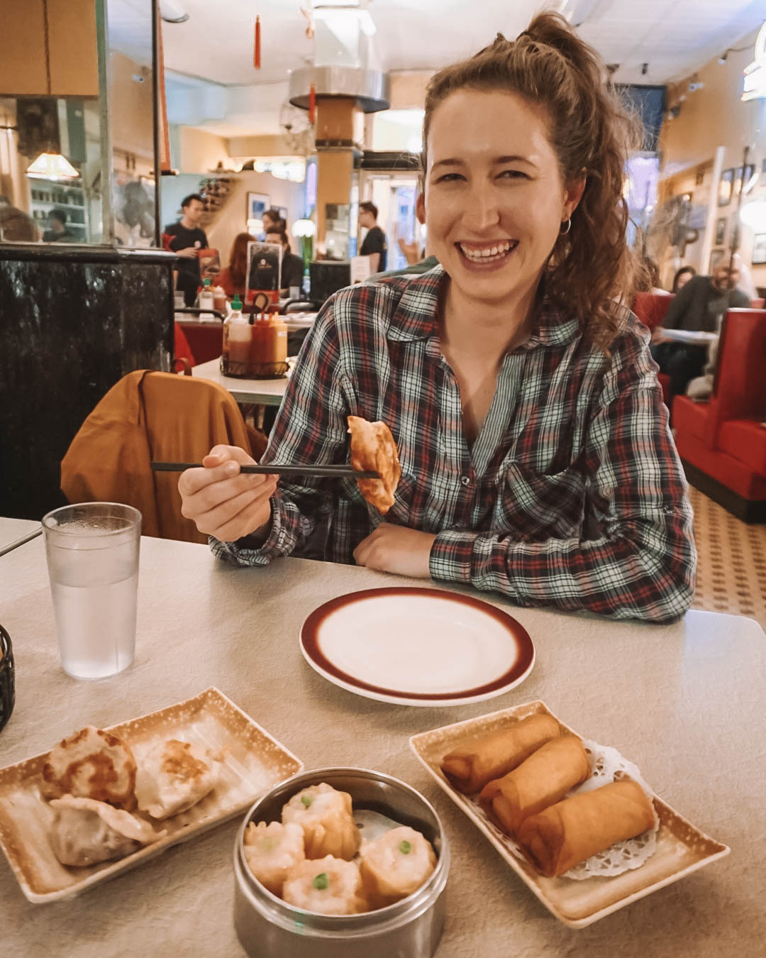 Girl holding up dim sum with chopsticks in dim sum restaurant. 