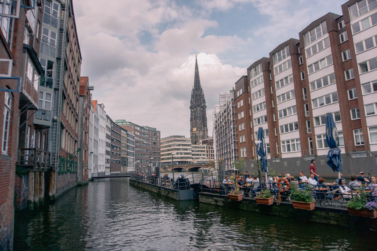 A canal in Hamburg, with a church steeple in the background. 