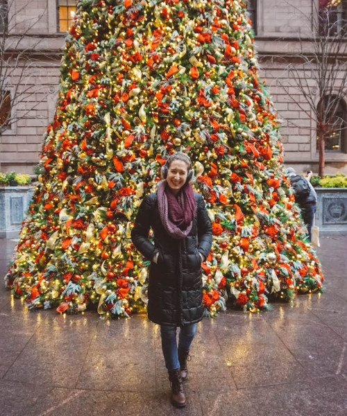 Woman standing in front of Lotte Palace Hotel Christmas Tree in NYC.