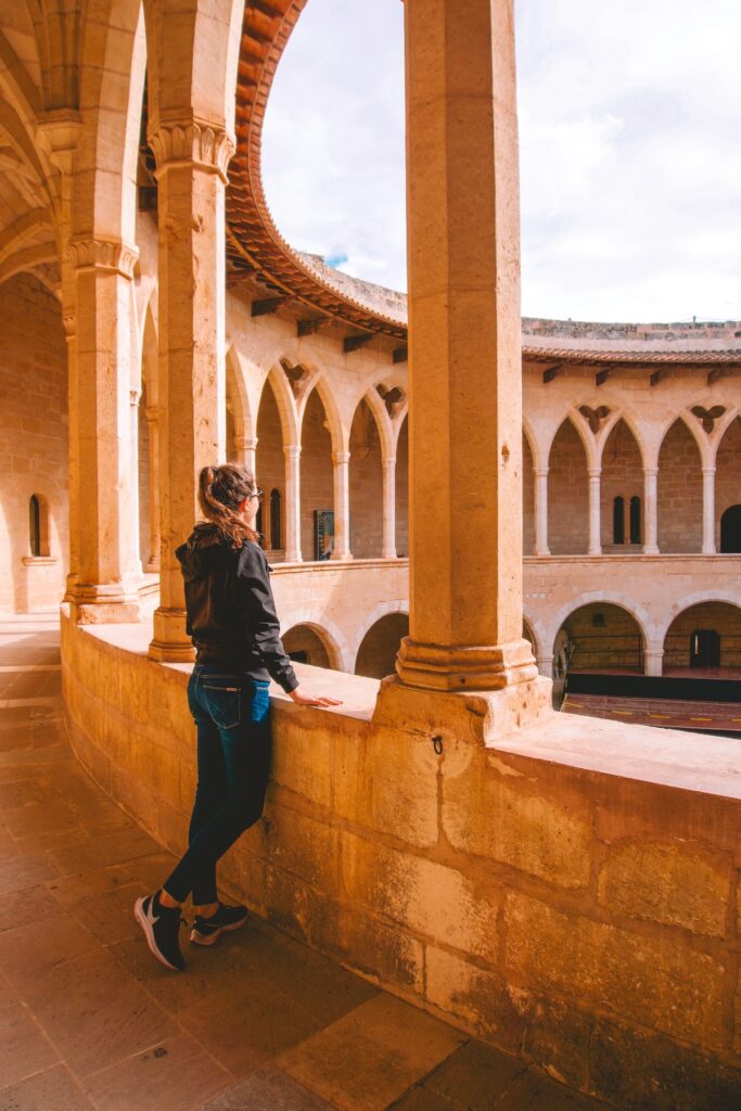 A woman looking out through an archway of the parade grounds at Castell de Bellver.