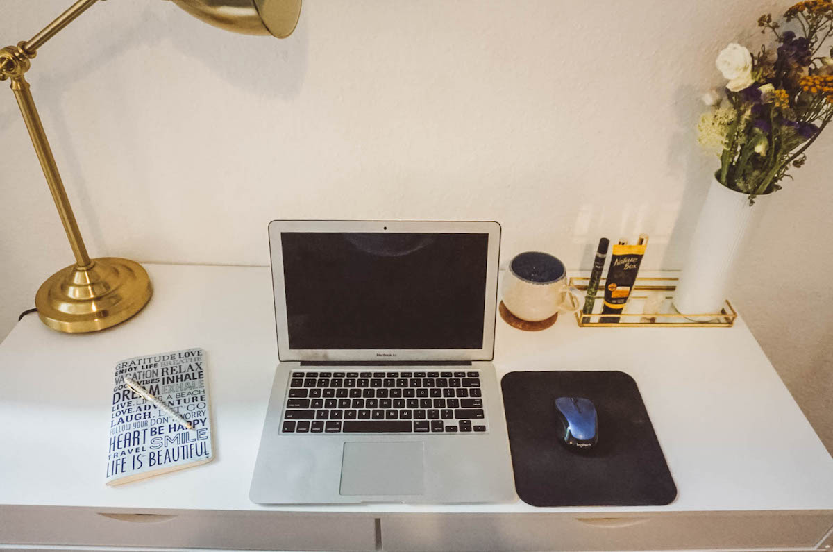 overhead view of work desk with laptop, notebook, and mousepad on it