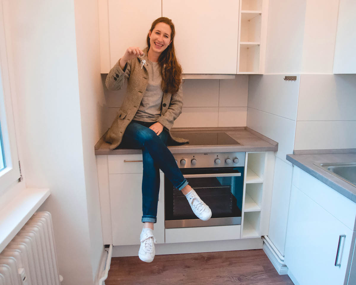 woman sitting on kitchen counter, holding up a set of keys