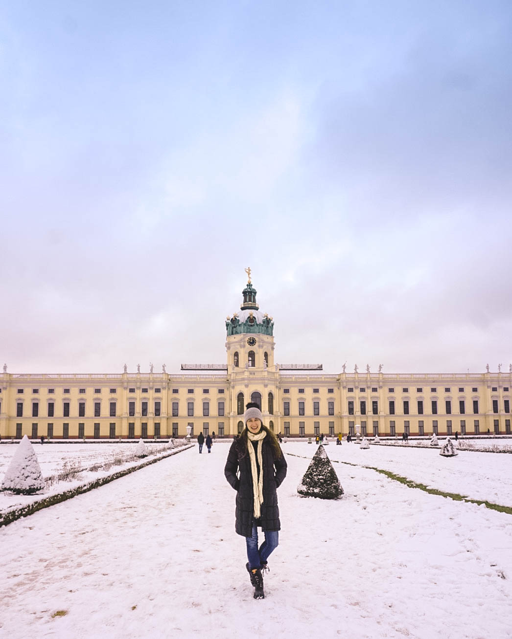 Woman standing in front of Charlottenburg Palace in Berlin. It's covered in snow. 