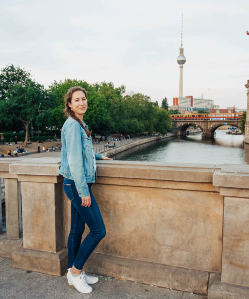 Woman standing on bridge with Berlin TV tower in the distance.