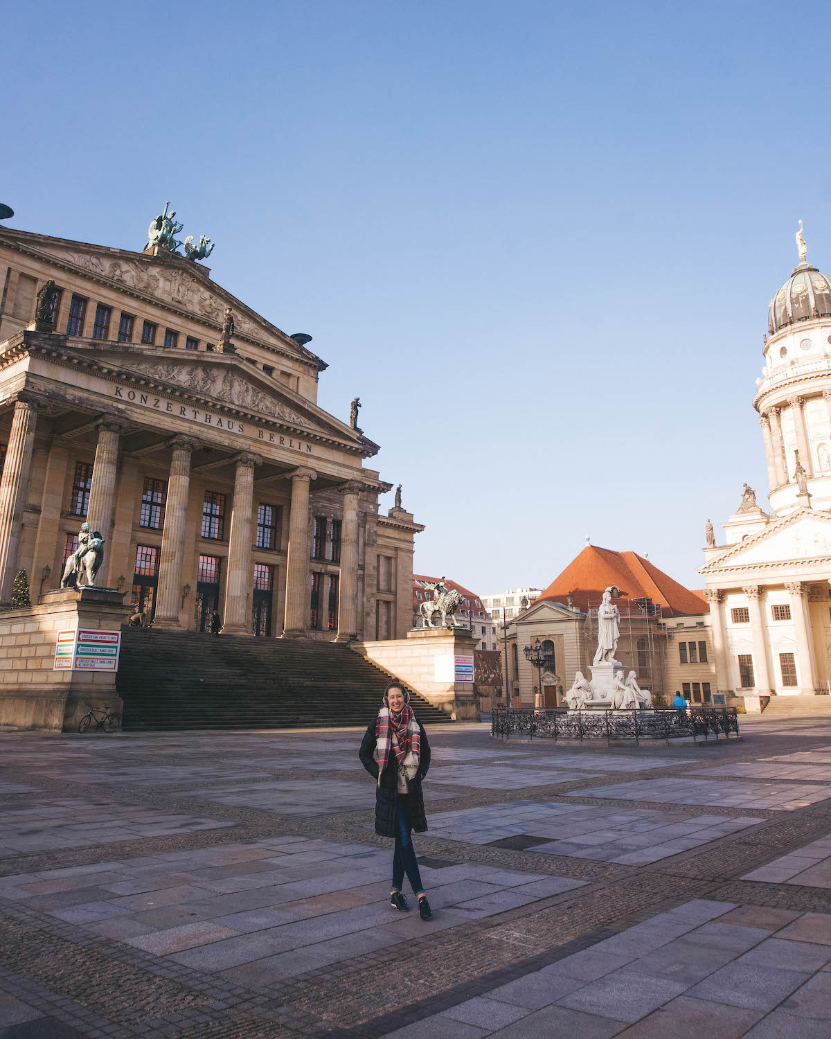 Woman smiling in front of the Konzerthaus at Gendarmenmarkt in Berlin.