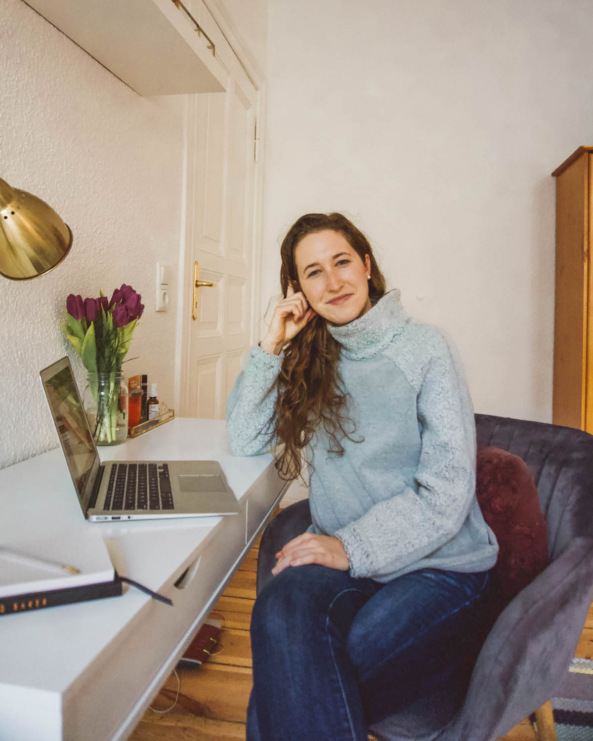 Woman sitting at desk, with elbow propping up her head. 