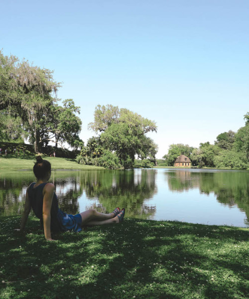 Woman leaning back on her hands, sitting by pond at Middleton Place.