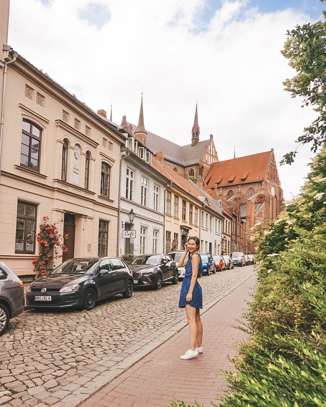 Woman standing on sidewalk near Church of St George in Wismar Germany.