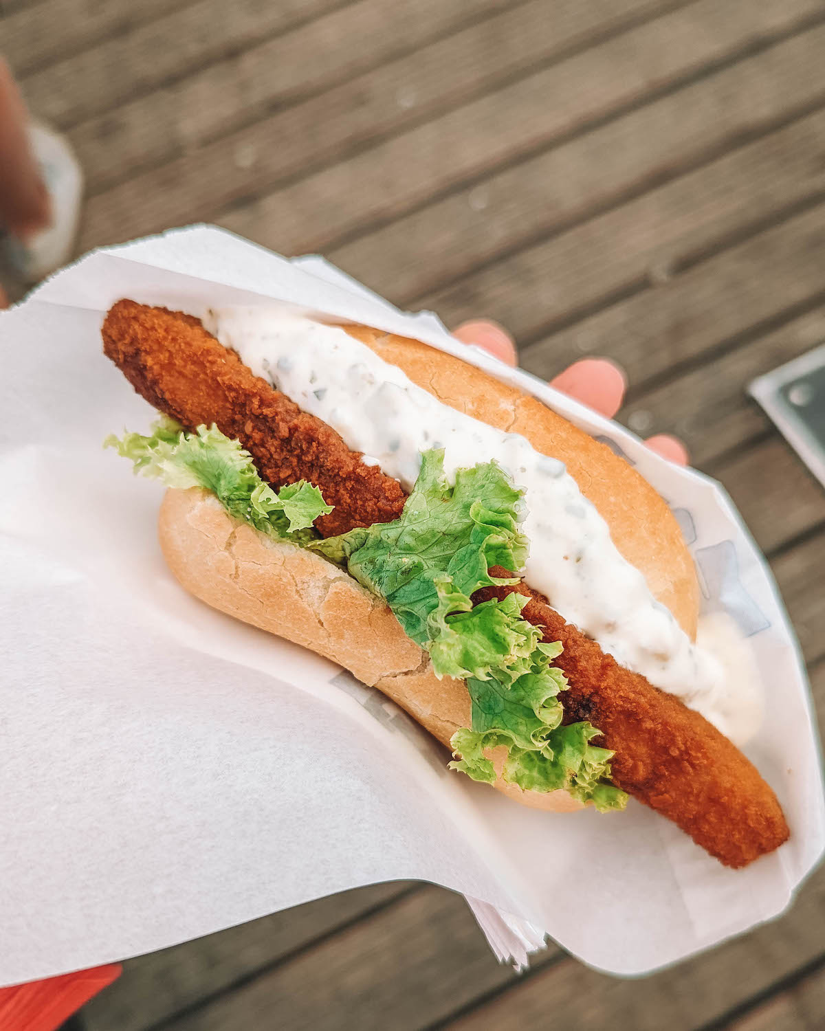 A fischbrötchen sandwich being held aloft