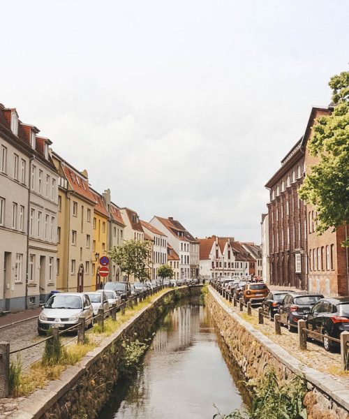 A waterway in Wismar traveling between two rows of houses.