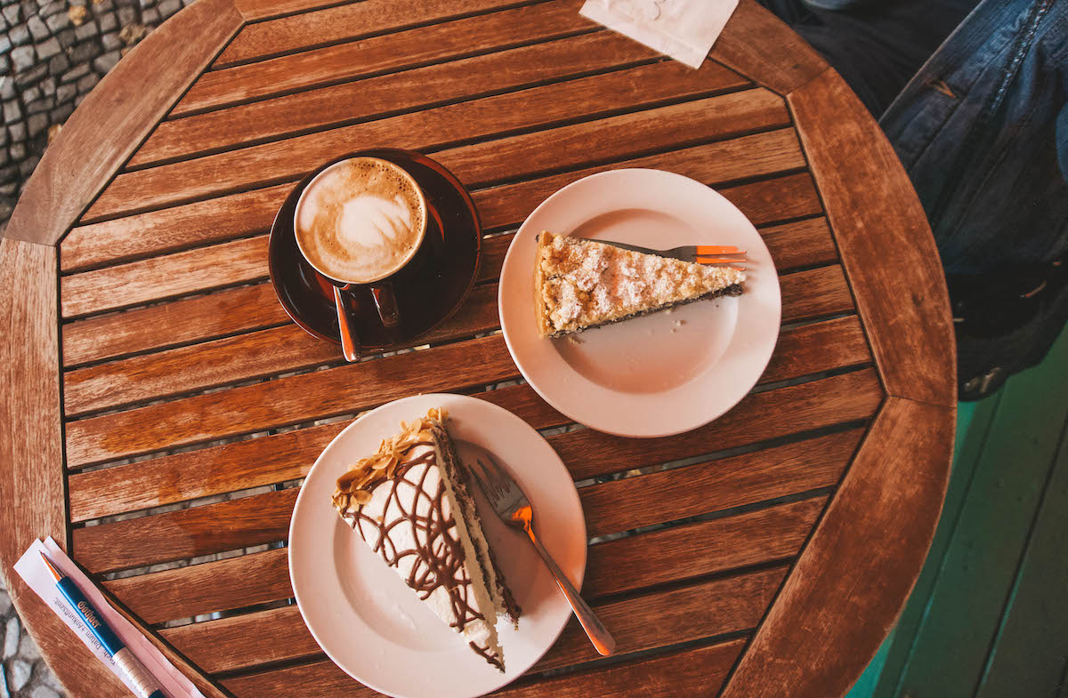 Overhead view of two slices of cake and a cup of coffee. 