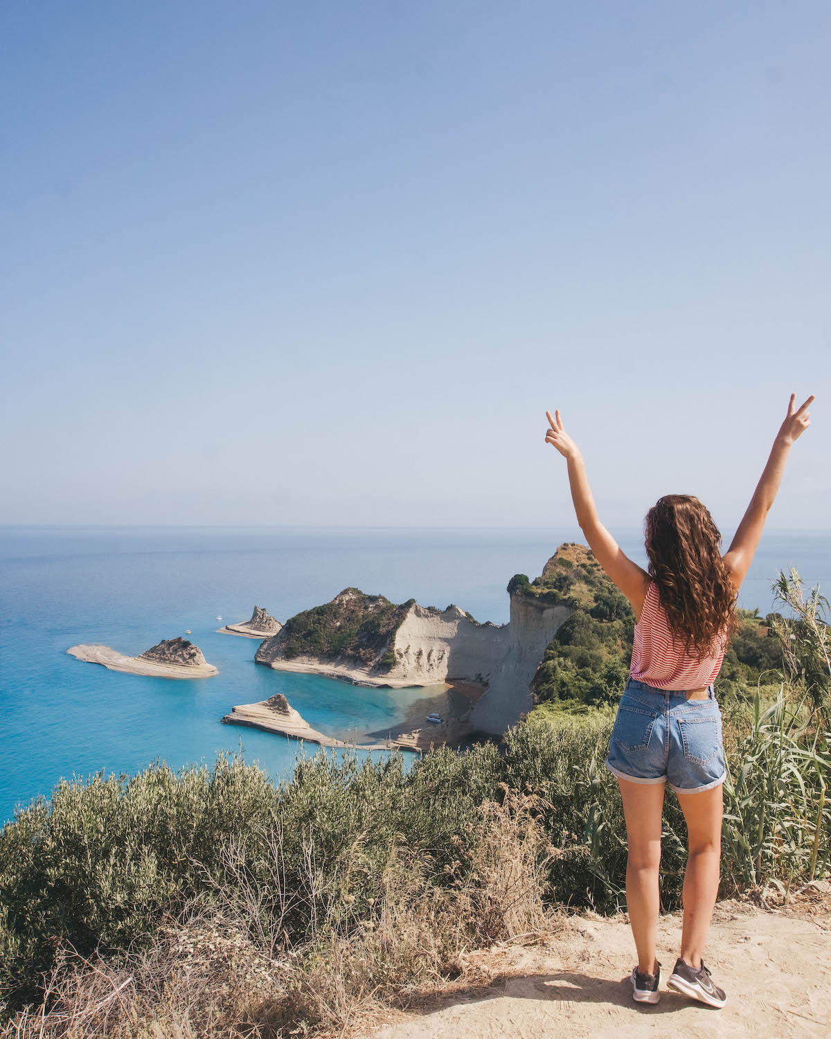 Woman with her back to the camera, in front of Cape Drastic on Corfu island in Greece. 