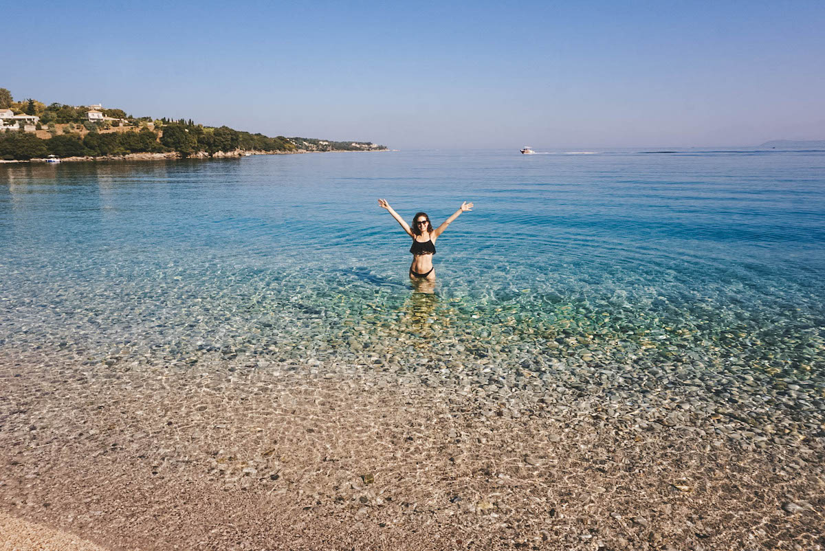 Woman standing in water with hands held aloft.