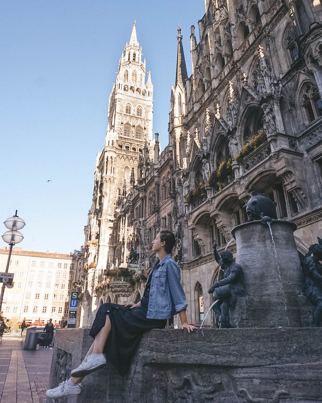 Woman sitting on Fish Fountain in Munich. 