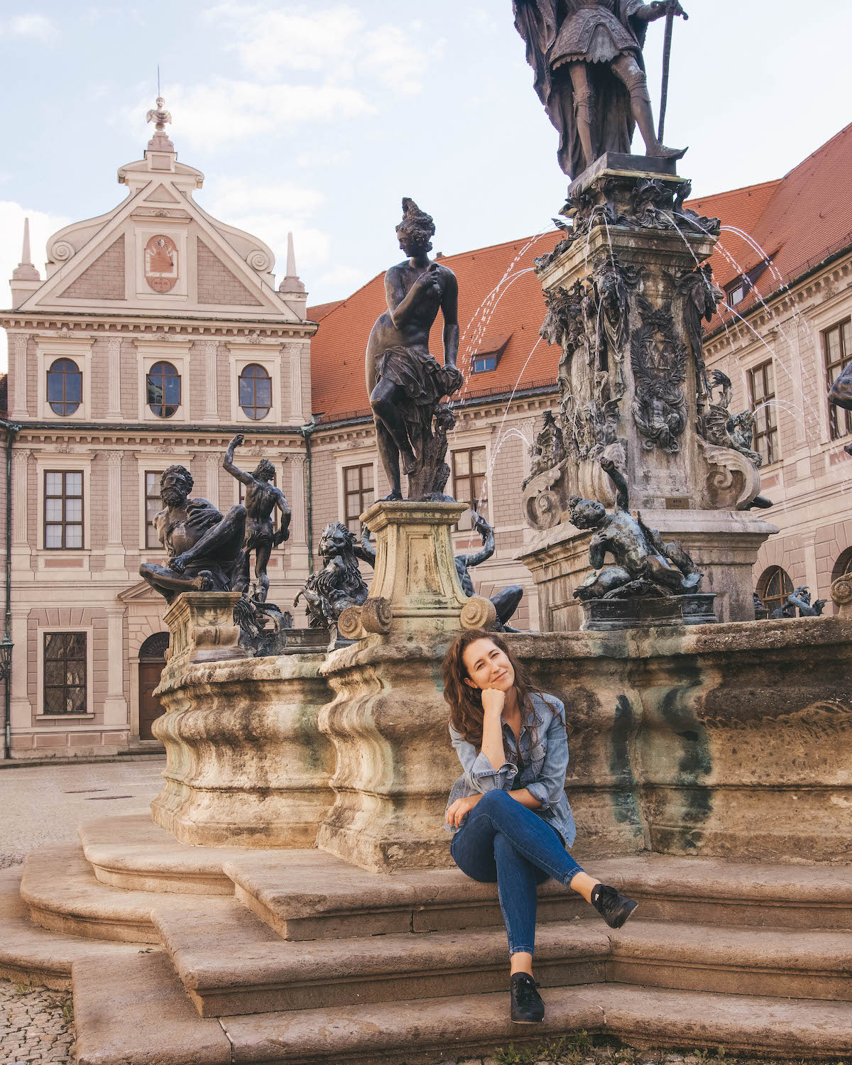 Woman sitting in front of fountain in Munich Residenz complex