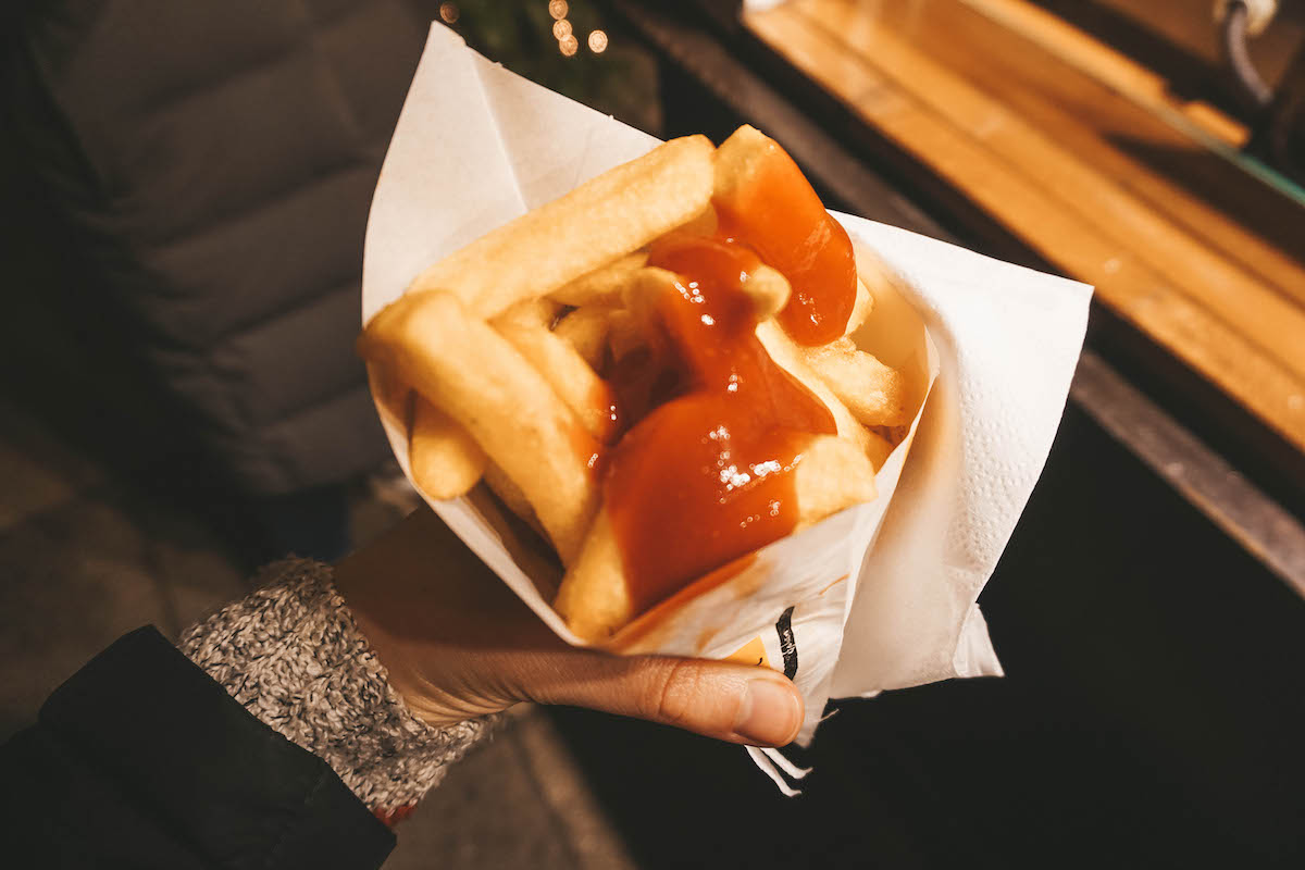 French fries topped with ketchup in a paper cone