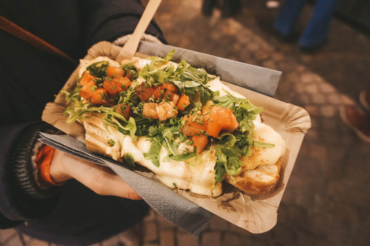 Bread topped with raclette cheese, arugula, and tomatos