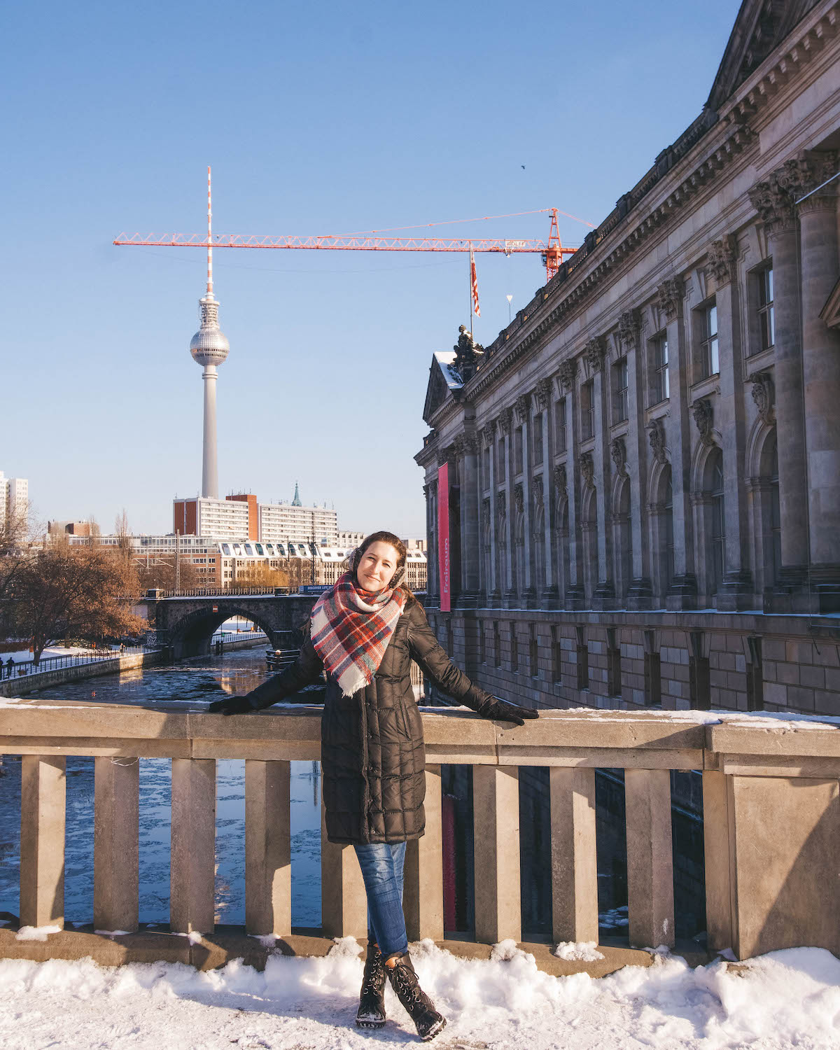 Woman standing on Berlin bridge in winter, snow is on the ground. 