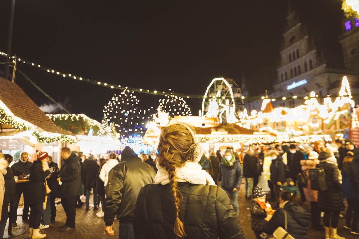 Woman's back as she looks at Christmas market by night
