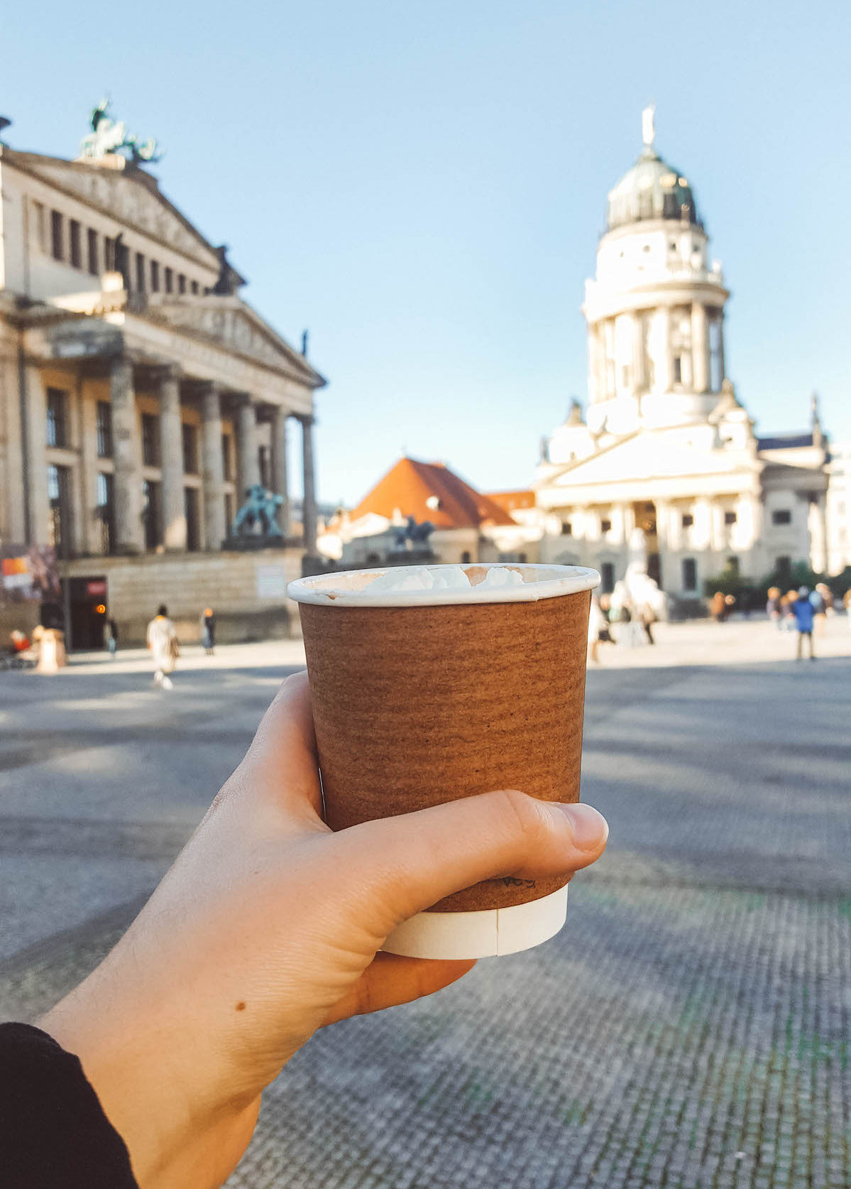 Cup of hot chocolate being held aloft at Gendarmenmarkt in Berlin