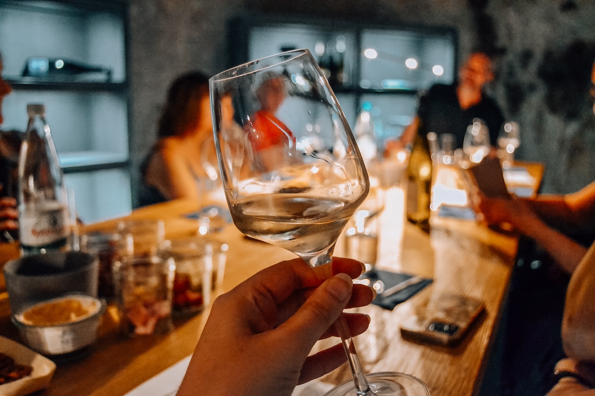 A wine glass held aloft at a wine tasting. 