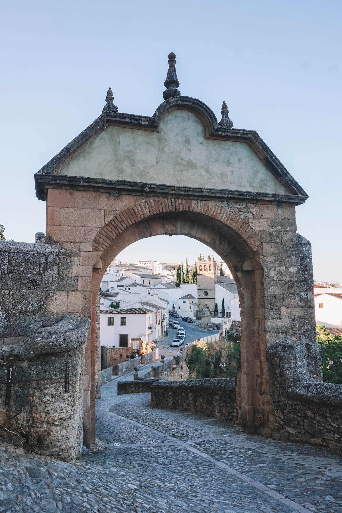 An archway in Ronda at dusk. You can see the Old Town through the archway. 