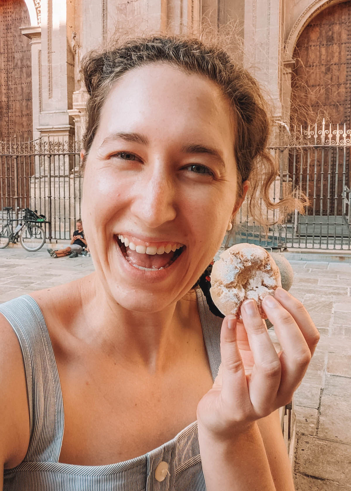 Woman holding up a cookie and smiling in Granada
