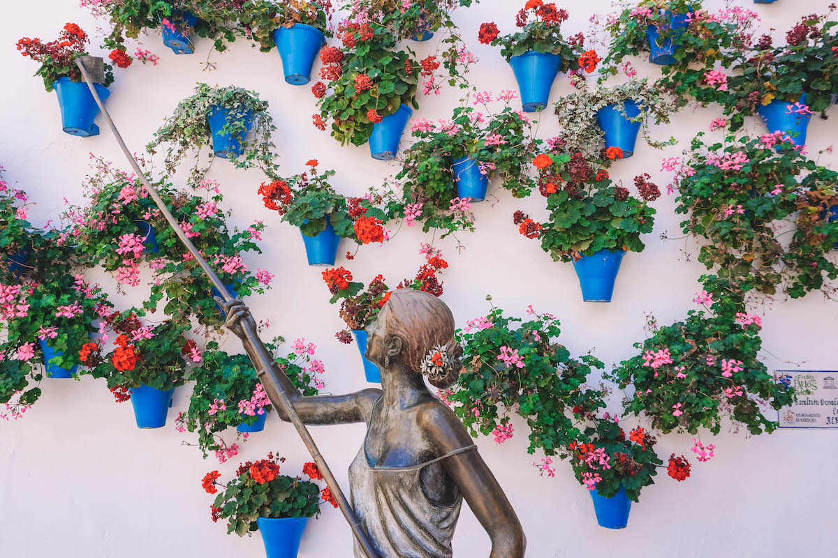 Bronze statue of a women tending to hanging flower pots in Cordoba, Spain 