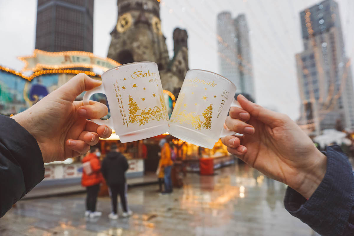 Two mulled wine mugs being held aloft at the Kaiser Wilhelm Memorial Church Christmas market. 