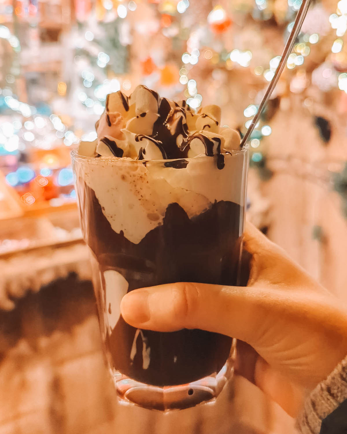 A decadent glass of hot chocolate topped with marshmallows and whipped cream, at a Christmas market 
