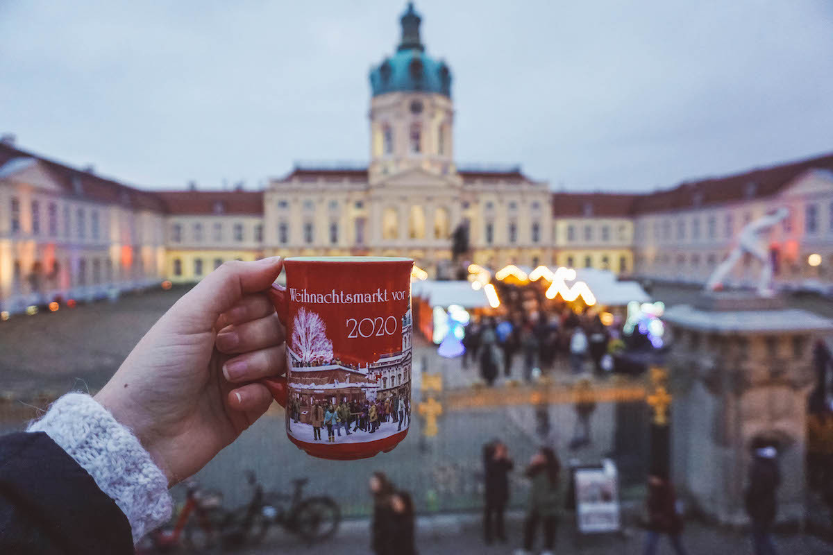 A mug of Glühwein held aloft at the Charlottenburg Palace Christmas market.