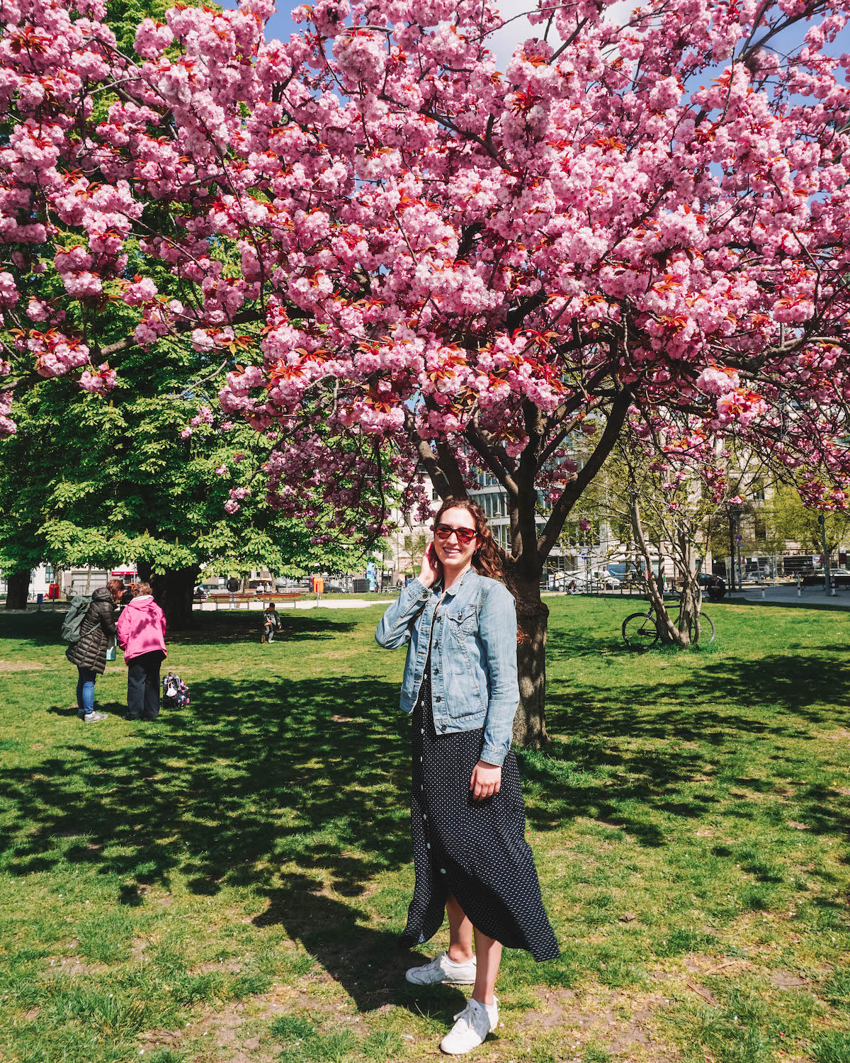 A woman smiling in front of a cherry blossom tree