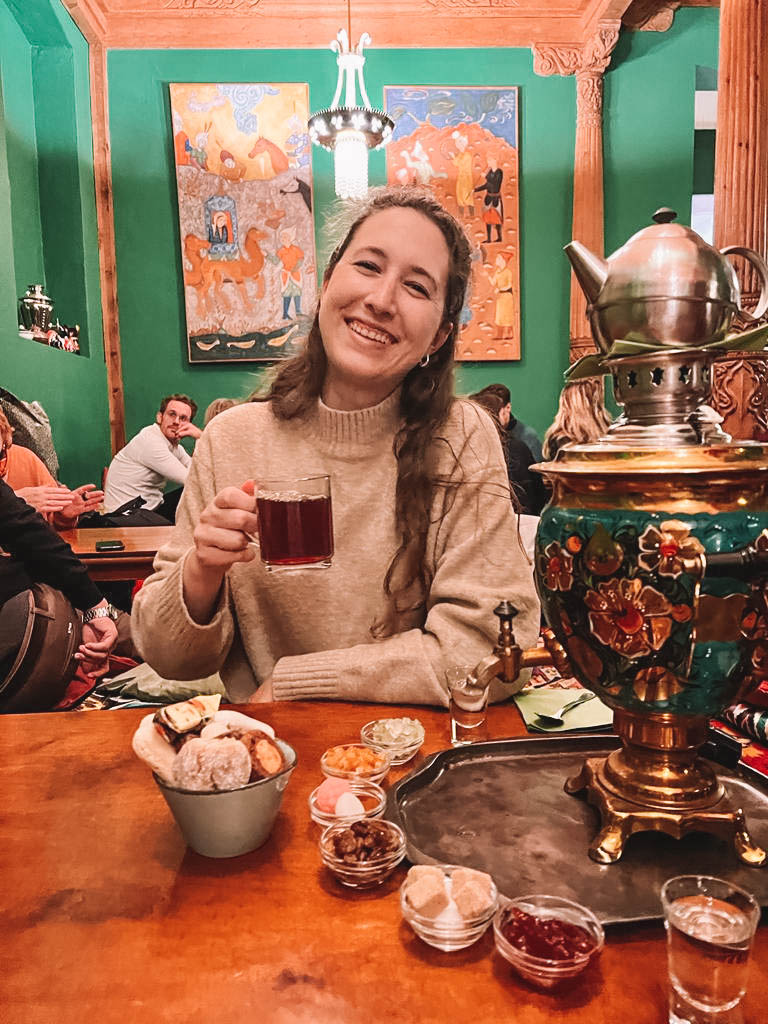 Woman holding cup of tea at Tajikistan Tea Room in Berlin. 