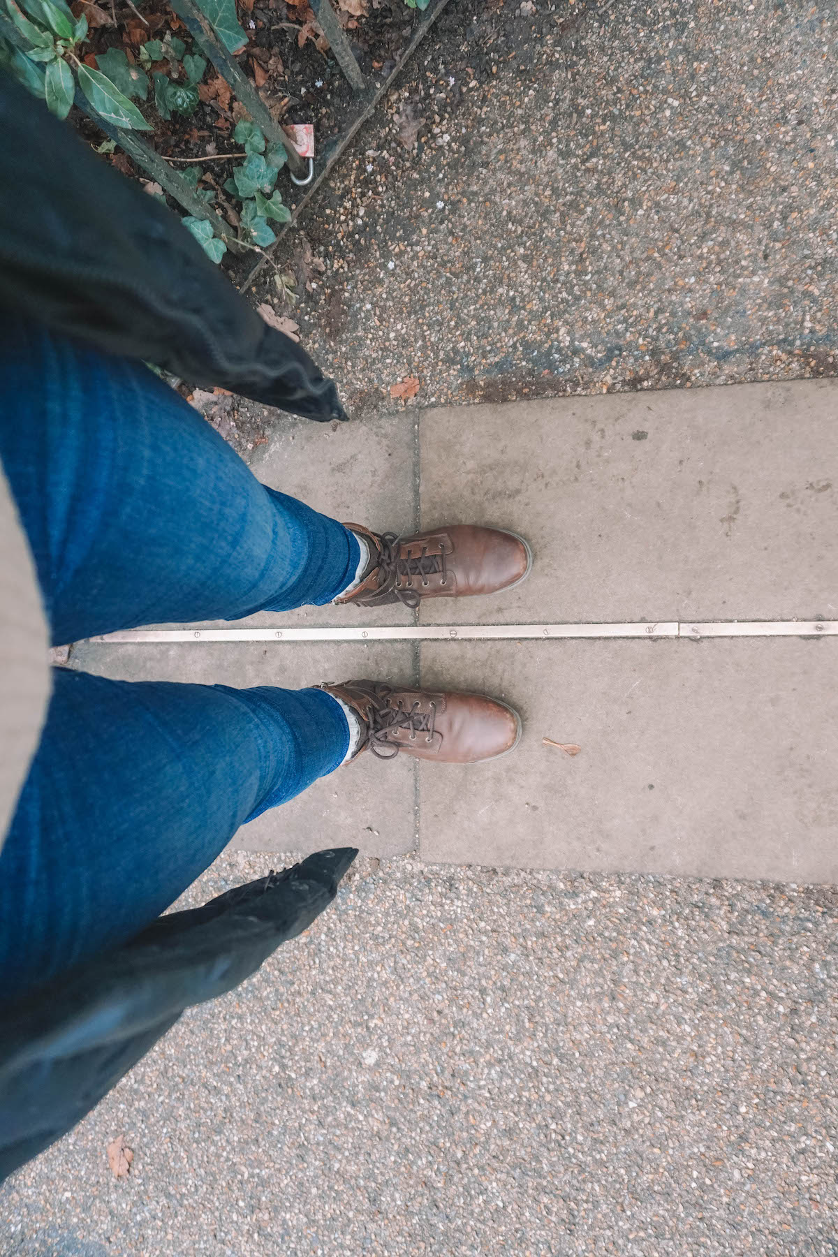 A woman's feet straddling the Prime Meridian line in Greenwich 