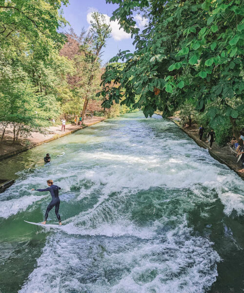 Surfers riding the waves at the Eisbach in Munich