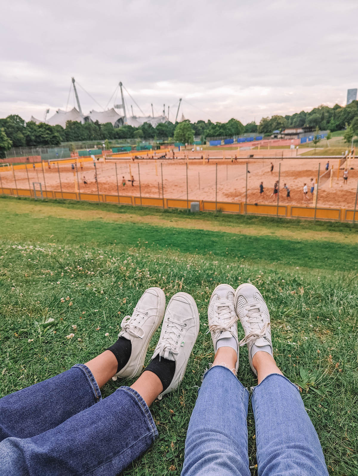 Two pairs of legs, on a hill in Olympiapark in Munich
