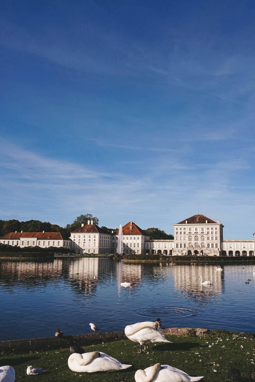 The front of Nymphenburg Palace in Munich, with swans on the water. 