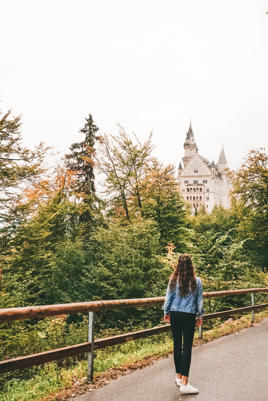 A woman looking at Neuschwanstein Castle, with her back turned to the camera. 