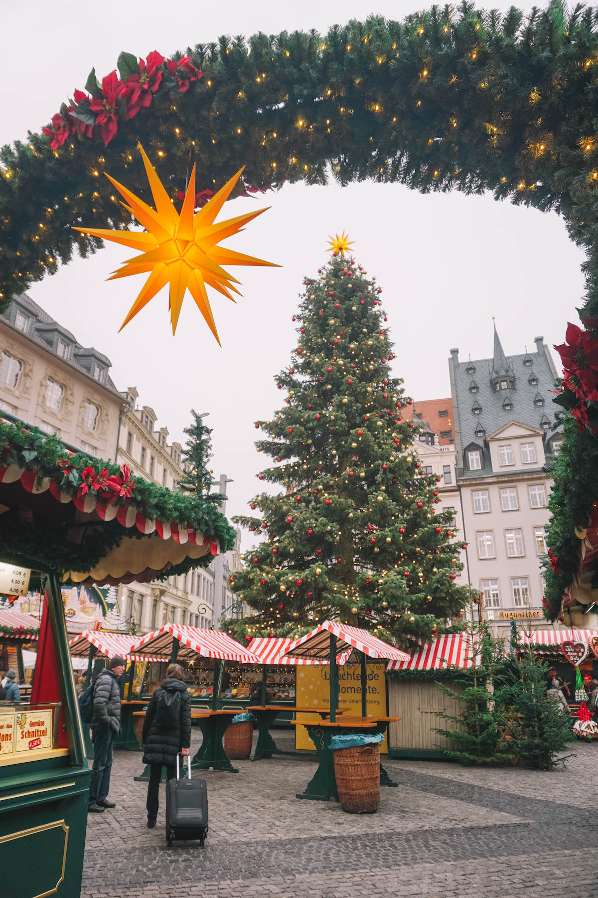 A tall Christmas tree surrounded by red and white-striped stalls at the Christmas market in Leipzig, Germany. 