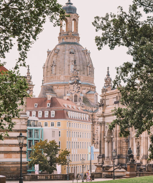 The Dresden Frauenkirche, seen through foliage in a park.