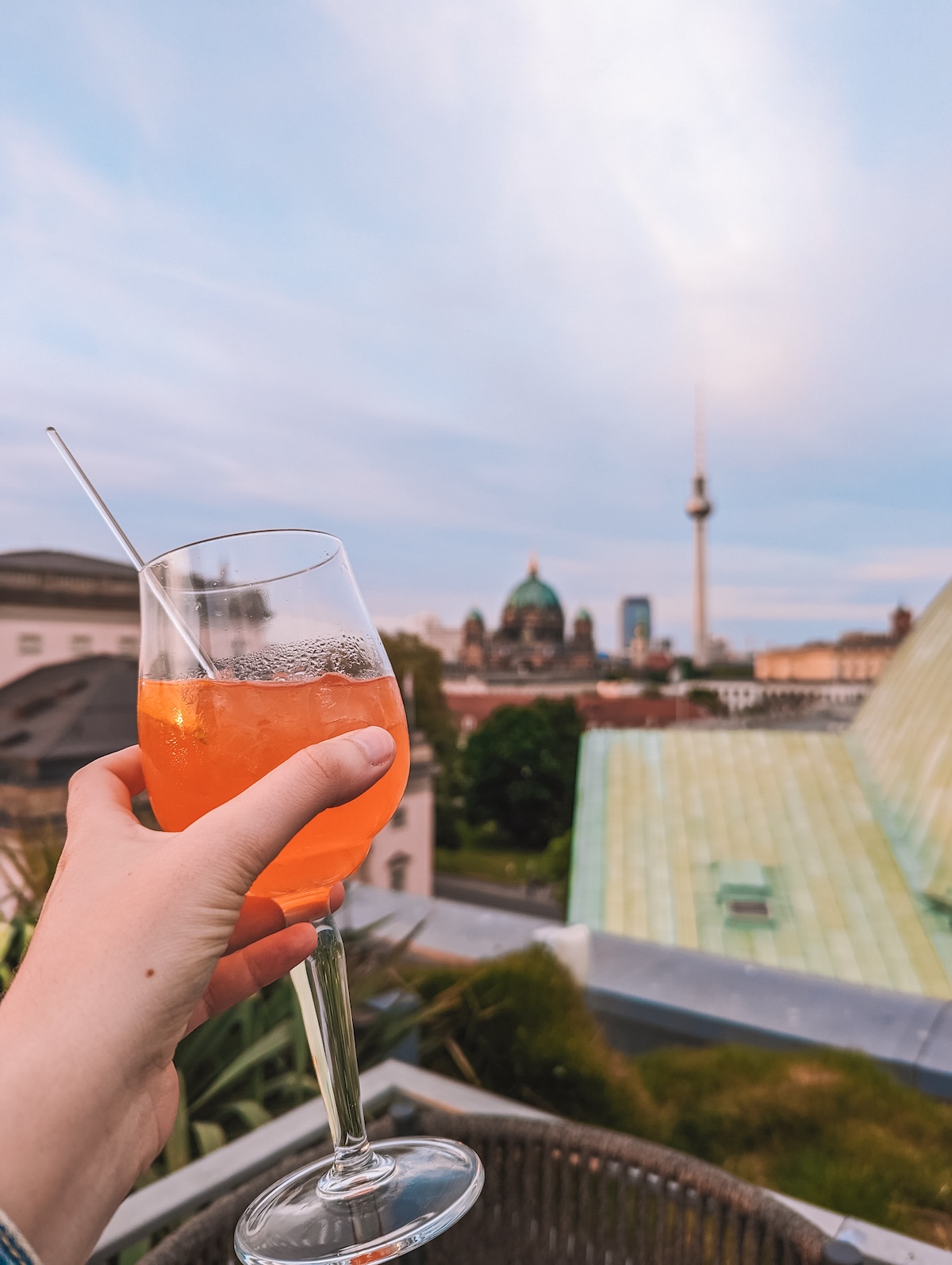 An Aperol spritz being held aloft from the Hotel de Rome rooftop bar.