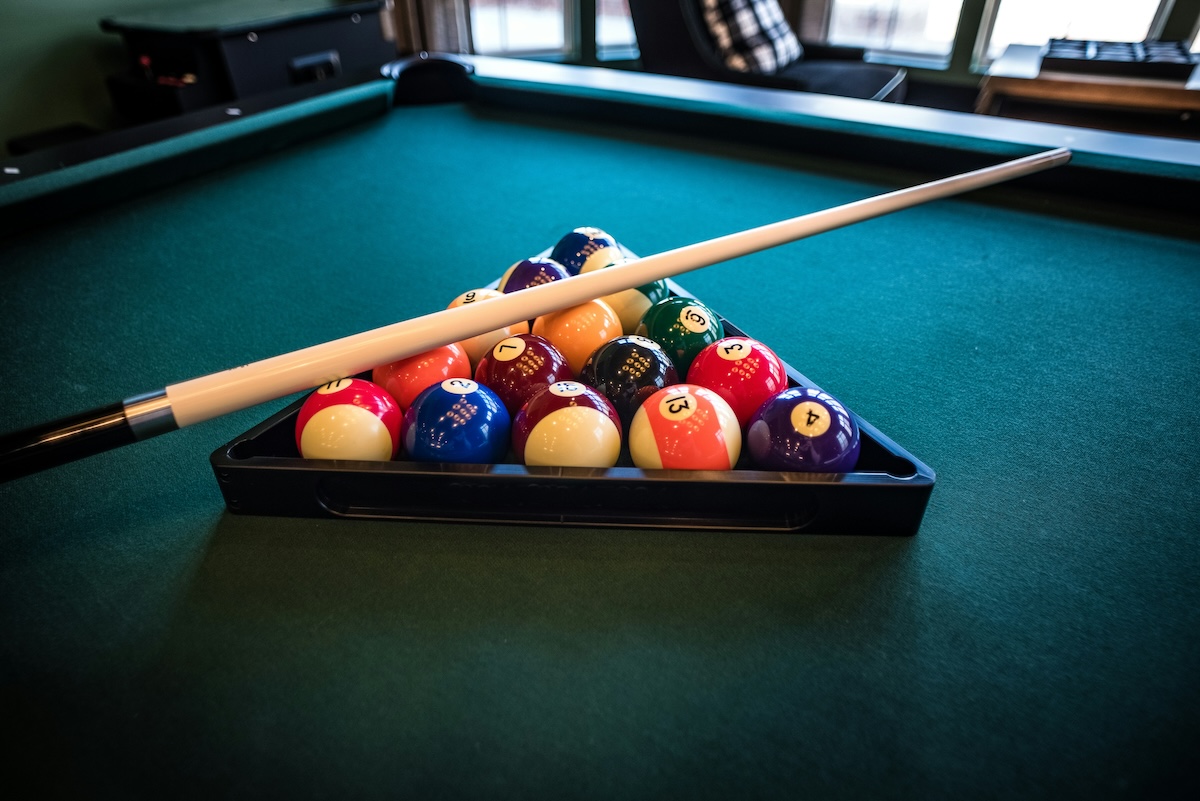 Pool table set up with balls and cue. 